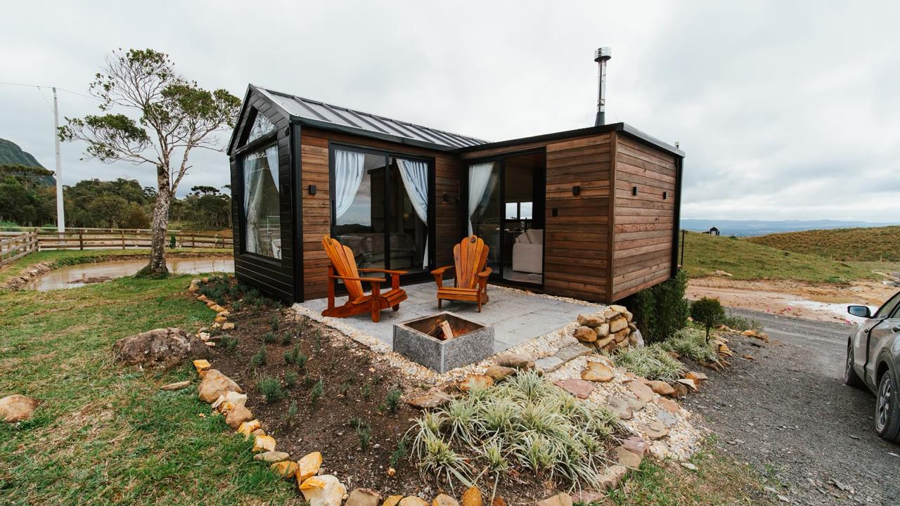 Cabana de madeira com poltronas e fogueira no jardim