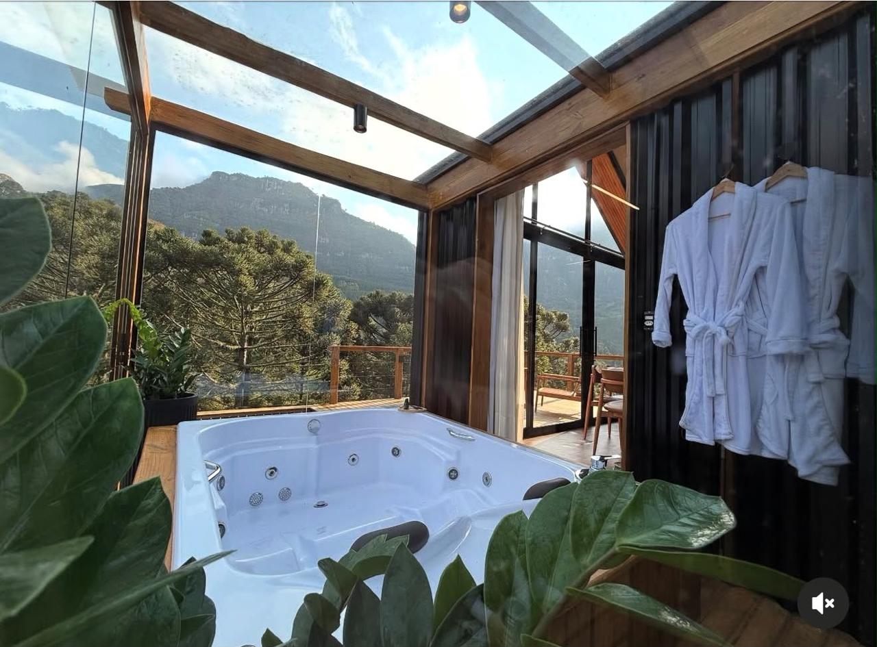 Hidromassagem em ambiente envidraçado com vista para a serra