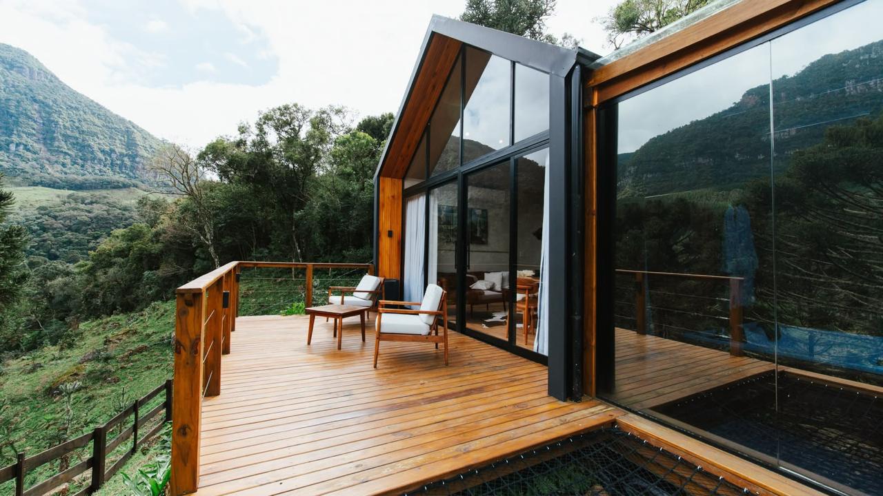 Deck de madeira com fachada envidraçada e vista para a serra